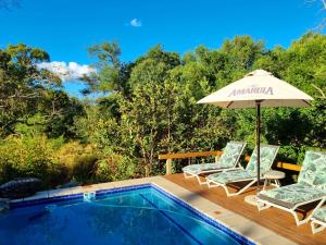 a swimming pool with two chairs and an umbrella at Kingfisher Creek Safari Lodge in Hoedspruit
