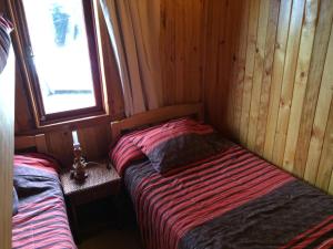 una piccola camera con due letti in una cabina di Cabañas Los Castaños a Licán Ray