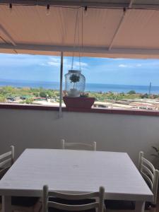 een witte tafel met stoelen en uitzicht op de oceaan bij Etna home in Santa Venerina