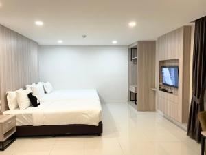 um quarto com uma cama e uma televisão de ecrã plano em BEAR’S DEN HOTEL PATTAYA em Praia de Jomtien