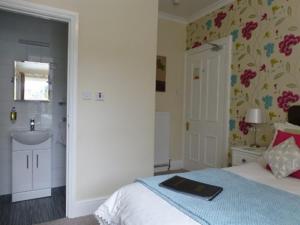ein Schlafzimmer mit einem Bett und ein Badezimmer mit einem Waschbecken in der Unterkunft Bryn Derwen Guest House in Conwy