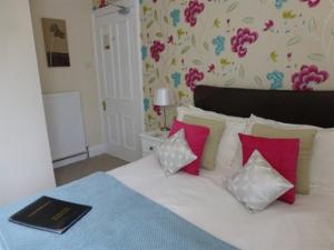 Schlafzimmer mit einem Bett mit rosa und weißen Kissen in der Unterkunft Bryn Derwen Guest House in Conwy