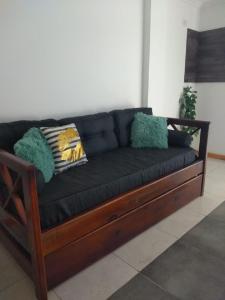 un sofá negro con almohadas en una habitación en Santino Apart en Puerto Iguazú