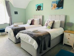 1 dormitorio con 2 camas con mantas en Whinburn Guest House, en Fort William