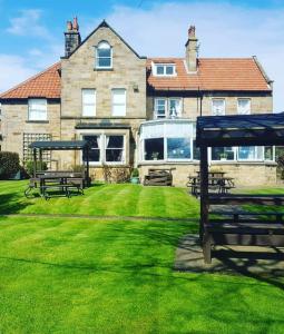a house with picnic tables and benches in the grass at The Fylingdales Inn in Whitby