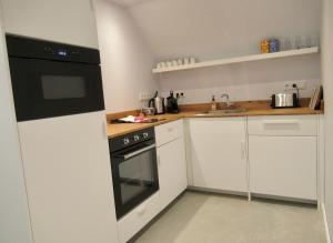 een keuken met witte kasten en een zwarte oven bij B and Be Happy Friesland in Lioessens