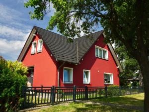 ein rotes Haus mit schwarzem Dach in der Unterkunft Ferienwohnung im roten Haus in Kröslin