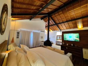 um quarto com uma grande cama branca e uma televisão em Pousada Serra da Índia em Penedo