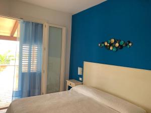 サン・ヴィート・ロ・カーポにあるVilla Ancora Bed & Breakfastの青い壁のベッドルーム(ベッド1台、窓付)