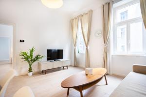 a white living room with a table and a tv at Modernes Apartment im charmanten Cottage Viertel in Vienna