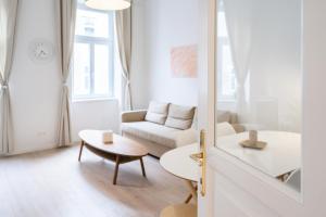 a white living room with a couch and a table at Modernes Apartment im charmanten Cottage Viertel in Vienna