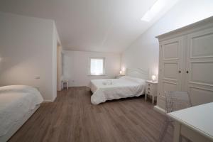 a white bedroom with two beds and a window at Agriturismo Corte Rondinella in Verona