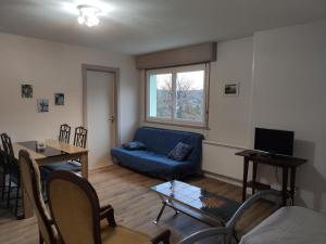 Una sala de estar con un sofá azul y una mesa. en LES TILLEULS, en Bains-les-Bains