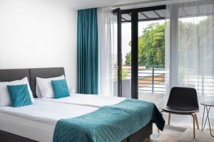 a bedroom with a bed and a chair and a window at Hotel Termalny in Uniejow
