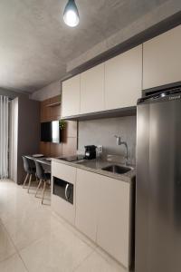 a kitchen with white cabinets and a stainless steel refrigerator at 360 Suítes Sé in Sao Paulo