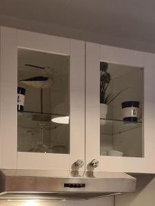 un armario de cocina blanco con 2 puertas de cristal con jarrones en bel-appartement-avec-terrasse, en Bad Schwartau