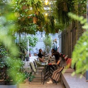 un groupe de personnes assises à une table dans un jardin dans l'établissement 21 House of Stories Città Studi, à Milan