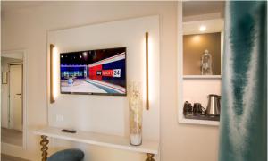 uma sala de estar com uma televisão na parede em Hotel Ambassador em Riccione
