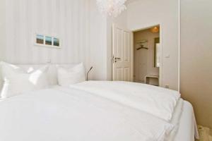 een wit bed in een witte slaapkamer met een spiegel bij Villa Waldschloss, App 01 in Heringsdorf
