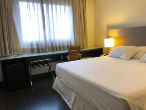 a hotel room with a large bed and a window at Hotel Gran Vivenzo Belo Horizonte in Belo Horizonte