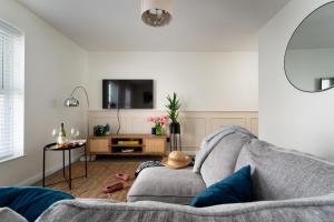 Lawsons Place - Family-Friendly Apartment with Parking on Babbacombe Downs in Torquay في توركواي: غرفة معيشة مع أريكة وتلفزيون