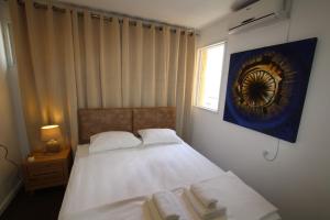 Schlafzimmer mit einem Bett mit weißer Bettwäsche und einem Fenster in der Unterkunft Isramax 3BR apartment near the sea. in Bat Yam