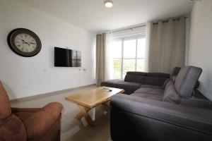 a living room with a couch and a clock on the wall at Isramax 3BR apartment near the sea. in Bat Yam