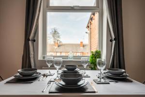 a table with plates and glasses on a table with a window at Hopetown Apartment-modern 2 bed with free parking in Normanton