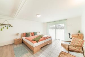 a white bedroom with a bed and a chair at Bah Apartment in Ljubljana