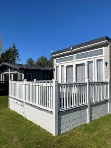 a white fence in front of a house at Lakeside Retreat Lodge With Hot Tub in Pocklington