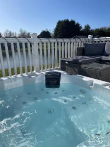 a jacuzzi tub in a backyard with a fence at Lakeside Retreat Lodge With Hot Tub in Pocklington