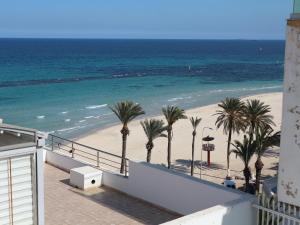 uma vista para uma praia com palmeiras e para o oceano em DESiGN UNQUE appartement em Sousse