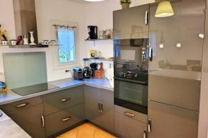 een keuken met grijze kasten en een fornuis met oven bij Beautiful House For 8 With Garden And Pool in Saint-Cyr-sur-Mer