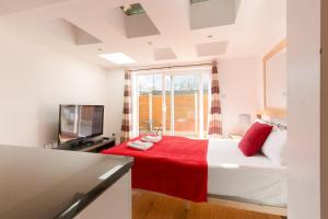 una camera con un letto con una coperta rossa e una TV di Centra Wharf a Londra