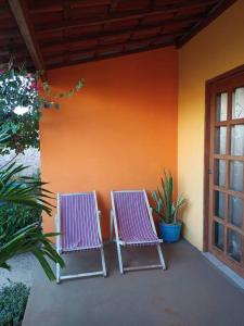 dos sillas moradas sentadas junto a una pared en Chalé Pitanga, en São Miguel do Gostoso