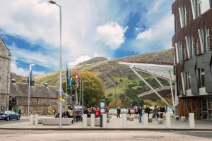 a group of people walking down a street with a mountain at Stunning 1 Bed at Holyrood Palace & Arthurs Seat in Edinburgh