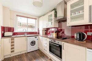 a kitchen with white cabinets and a sink and a dishwasher at Stunning 1 Bed at Holyrood Palace & Arthurs Seat in Edinburgh