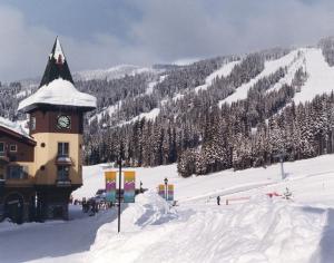 a building with a clock tower in the snow at Sundance Lodge in Sun Peaks