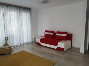 ブラショヴにあるExquisite Apartamentのベッドルーム(赤と白のベッド、カーテン付)