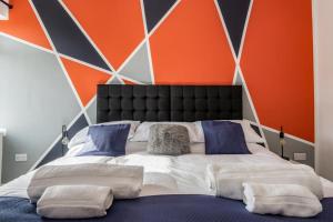 Cama grande en habitación con pared de color naranja en Hopetown Apartment-modern 2 bed with free parking en Normanton