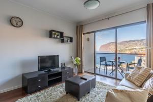 a living room with a tv and a large window at Centromar Residence Ocean View By Atlantic Holiday in Funchal