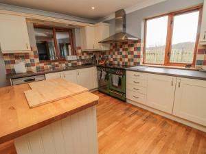 uma cozinha com armários brancos e um balcão de madeira em Ridley Lodge em Morpeth