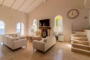 soggiorno con sedie e orologio sul muro di Magnífica villa cerca Sotogrande con vista mar excepcional a Manilva