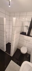a white tiled bathroom with a toilet and a sink at FeWo Püttlingen 1 in Püttlingen