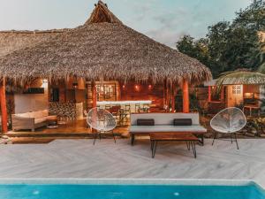 a villa with a pool and a thatch roof at El Pez Surf Hotel in Popoyo