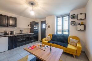 a living room with a yellow couch and a table at CHOUETTISSIME Topséjour-Roanne 1 chambre All Inclusive in Roanne