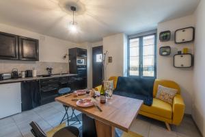 a kitchen and living room with a table and a couch at CHOUETTISSIME Topséjour-Roanne 1 chambre All Inclusive in Roanne