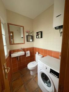a bathroom with a toilet and a washing machine at Sueños de Monfrague in Torrejón el Rubio