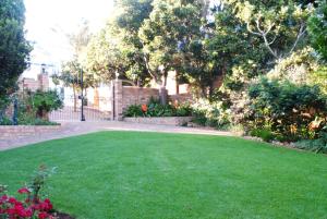 a yard with green grass and flowers and a fence at Remini in Jeffreys Bay