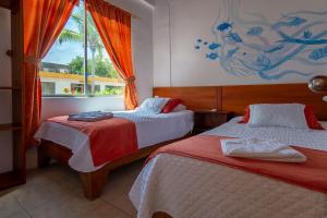 ein Hotelzimmer mit 2 Betten und einem Fenster in der Unterkunft Hotel Coral Blanco with high speed internet Starlink in Puerto Villamil